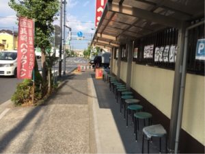 東京都足立区にある島田屋製菓の店舗前に常設されている18席の椅子。老若男女を問わず大人気のタイムサービスの開始時間まで座って待つことができる粋な計らいだ。